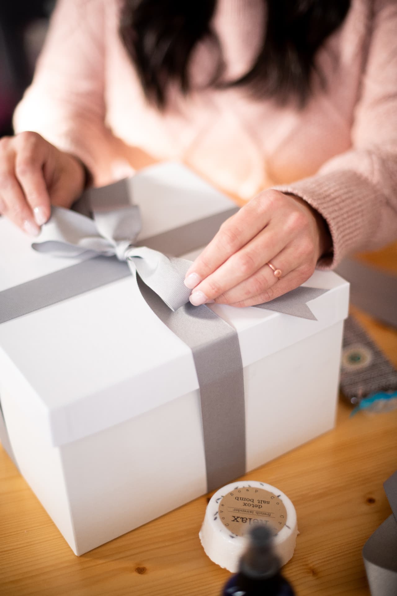 Hands tying a satin ribbon on a white gift box